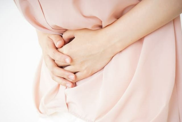 腹痛でお腹を押さえる女性